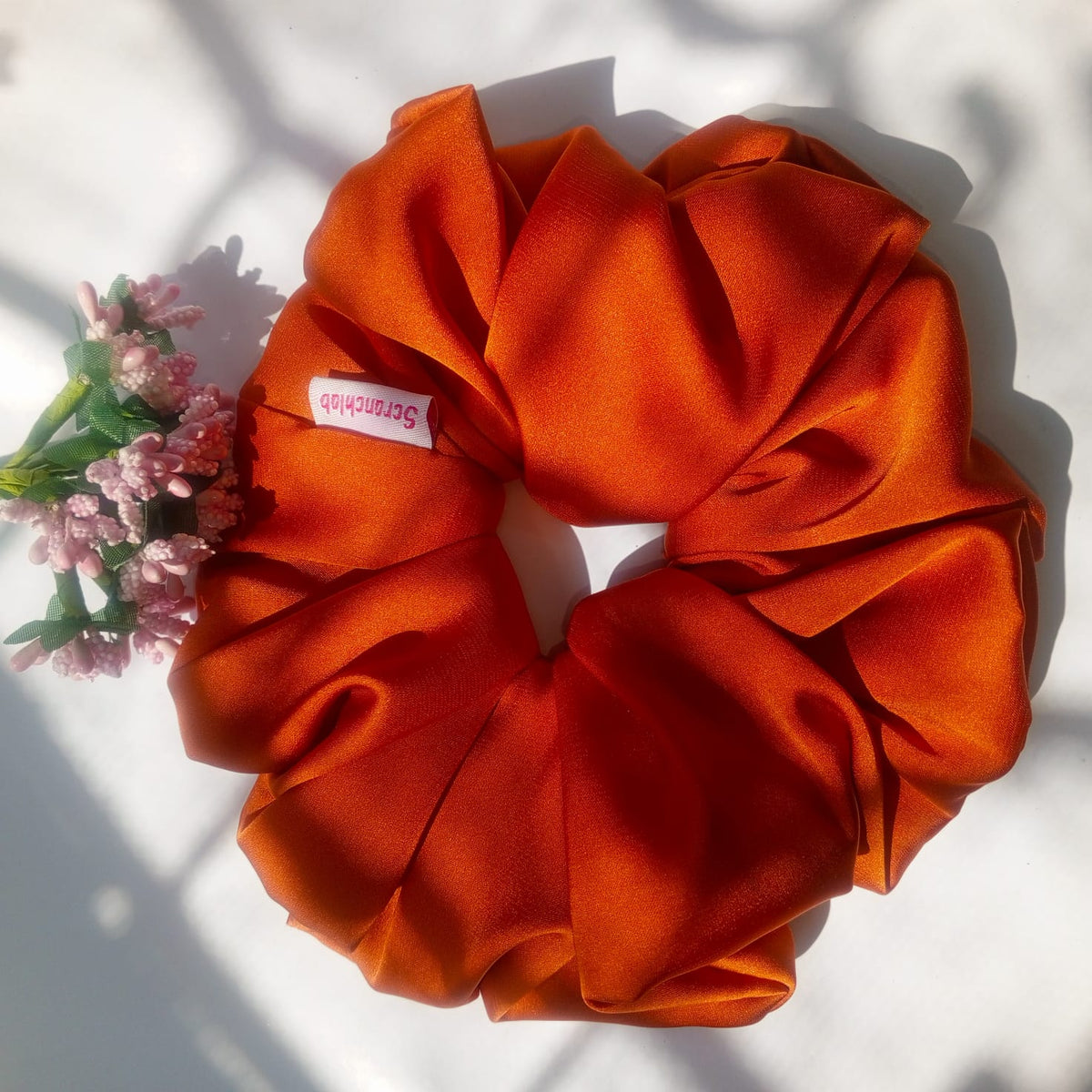 Scranchlab Rust Silk Scrunchie - angled view with flowers